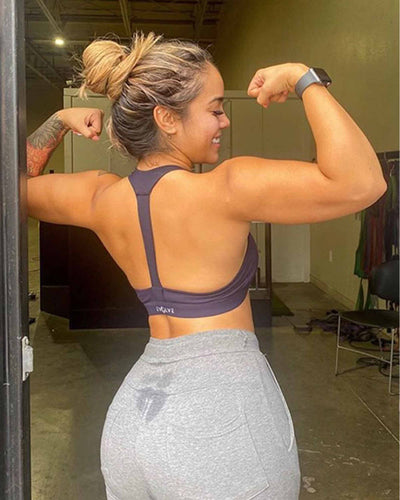 Woman in workout attire flexing her muscles in a gym setting
