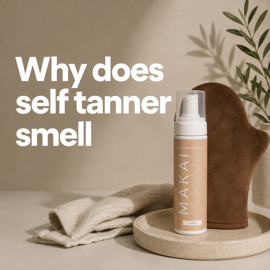 MAKAI self-tanning mousse bottle and brown tanning mitt styled with folded towels on a neutral tray, with text reading “Why does self tanner smell.”